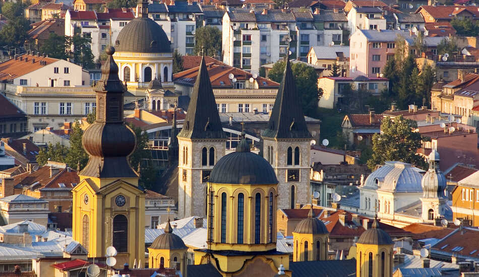 2023/04/images/tour_1264/sarajevo-rooftops-with-catholic-and-orthodox-cathedralscharles-bowmangettycs.jpg